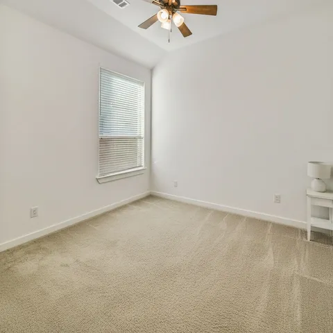 an empty room with a ceiling fan and a window