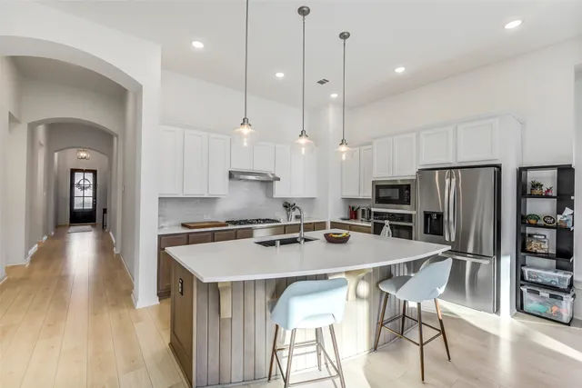 a kitchen with stainless steel appliances a dining table chairs refrigerator and stove