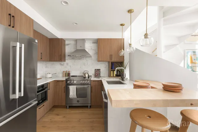 a kitchen with a stove a refrigerator and chairs
