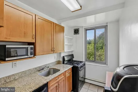 a kitchen with stainless steel appliances granite countertop a sink dishwasher a refrigerator a stove with wooden cabinets