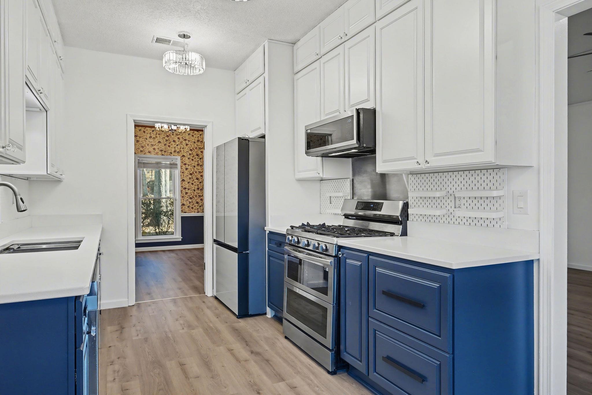 8431 Bazemore Road Cordova, TN 38018 - Photo 3 of 23 Dual tone cabinets, stainless steel appliances, stainless steel backsplash with custom adjustable pegboard storage, and modern lighting.