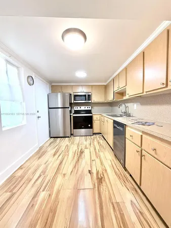 a kitchen with granite countertop a refrigerator oven a sink dishwasher and white cabinets with wooden floor