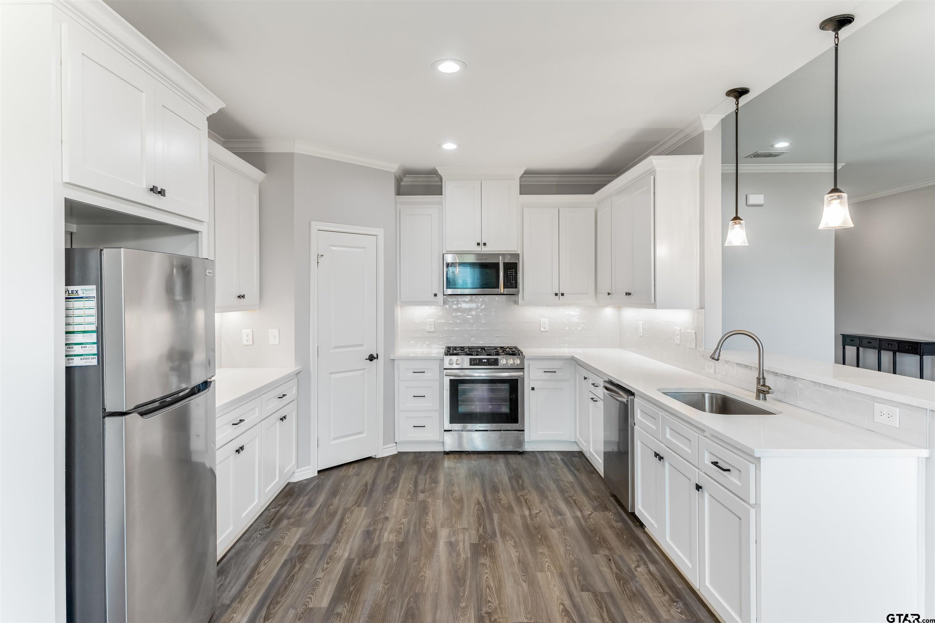 12908 County Road 46 Tyler, TX 75704 - Photo 15 of 24 a kitchen with stainless steel appliances granite countertop a refrigerator a sink dishwasher a stove and white countertops with wooden floor