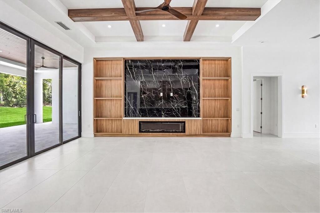 14318 Charthouse Circle Naples, FL 34114 - Photo 6 of 36 a view of an empty room with a fireplace and a chandelier