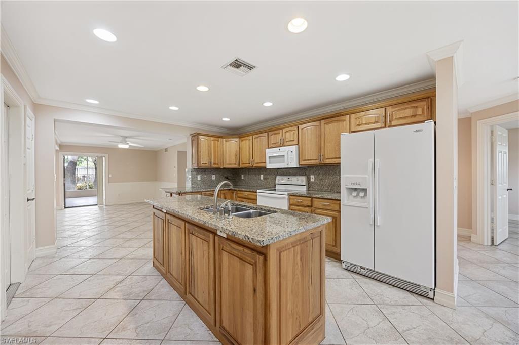 1120 Ridge Street Naples, FL 34103 - Photo 15 of 39 Kitchen featuring large island, ample counter space, white appliances, ornamental molding, tasteful backsplash, light stone counters, and recessed lighting
