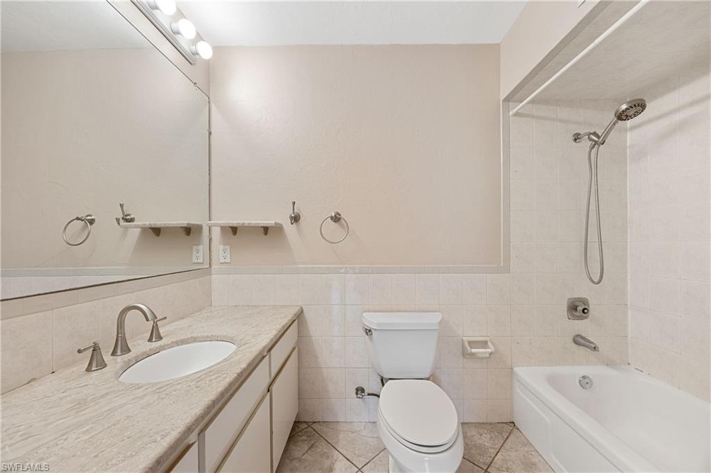 1120 Ridge Street Naples, FL 34103 - Photo 33 of 39 Primary ensuite Full bath / Shower,Tub combination, vanity, a wainscoted wall, tile patterned floors, and tile walls.