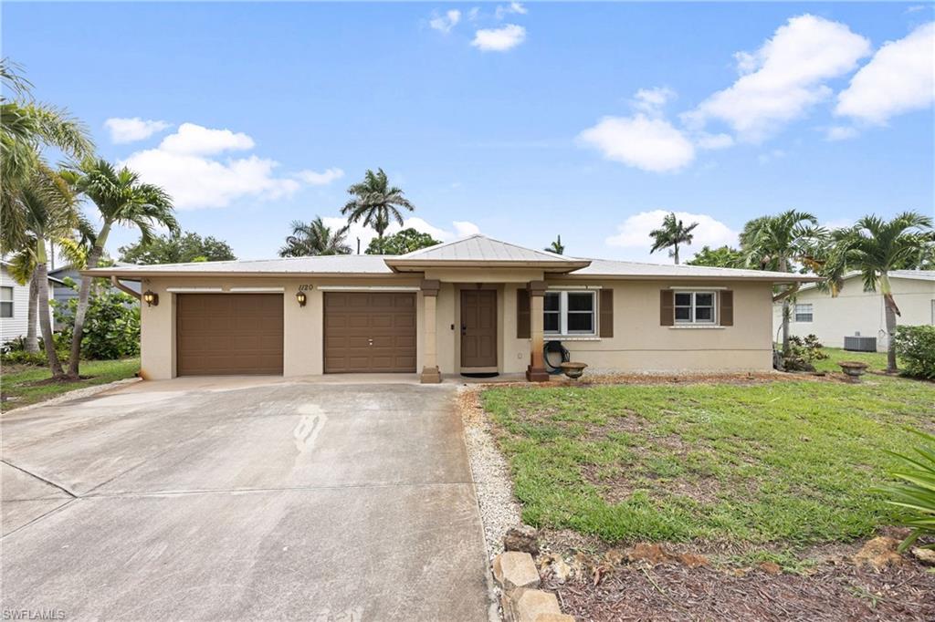 1120 Ridge Street Naples, FL 34103 - Photo 4 of 39 View of front facade featuring a 2 Car garage, concrete driveway, a front yard, stucco siding, and a metal roof