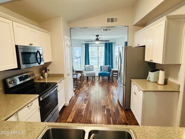 a kitchen view with wooden floor a sink and a stove top oven