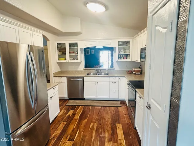 a kitchen with a refrigerator a sink and dishwasher with wooden floor