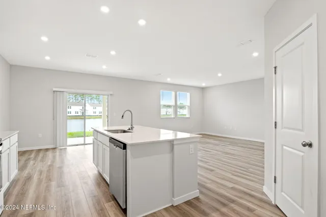 a kitchen with kitchen island a sink wooden floor and white stainless steel appliances