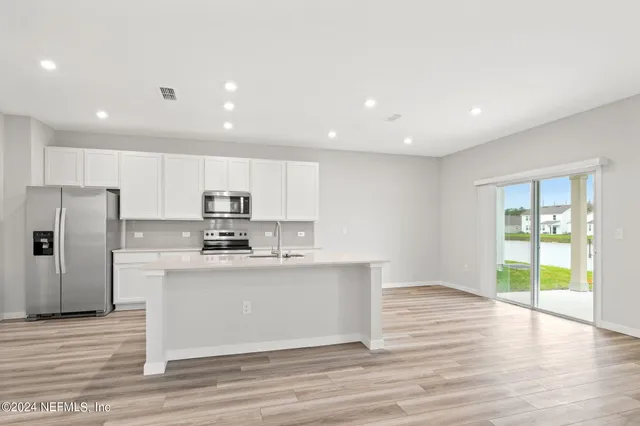 a kitchen with stainless steel appliances granite countertop a sink a stove a refrigerator and a microwave