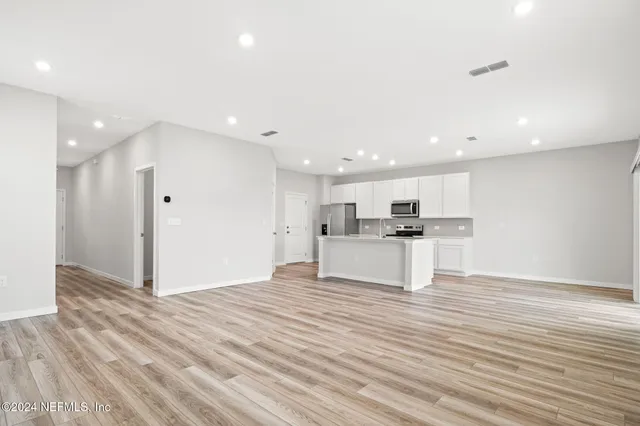 a view of kitchen with kitchen island a sink wooden floor and white appliances