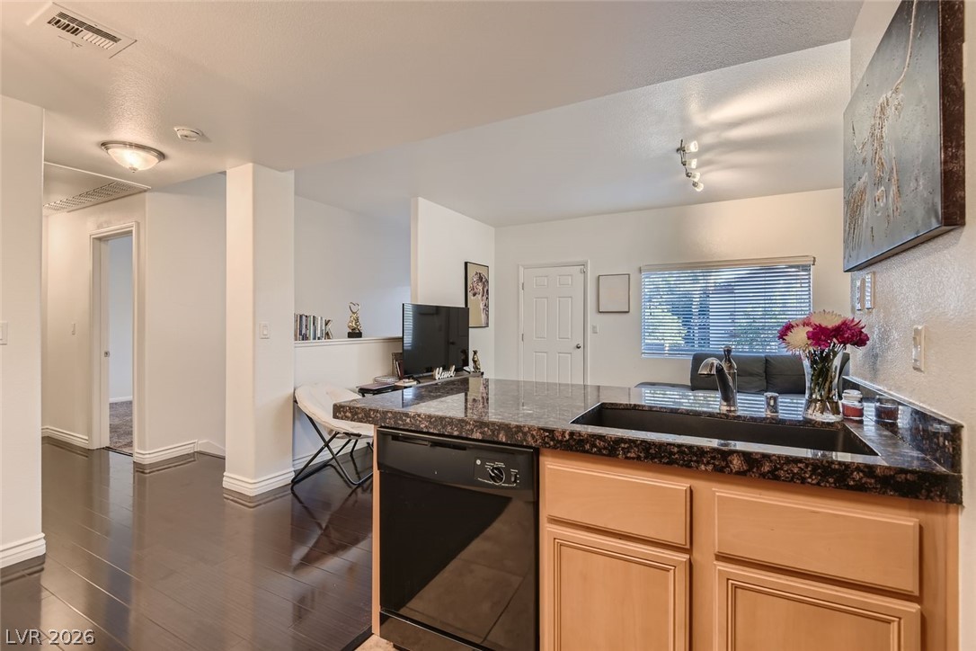 7701 West Robindale Road, Unit 265 Las Vegas, NV 89113 - Photo 11 of 27 Polished dark floors contrast beautifully with classic wooden cabinetry and sleek stone countertops.