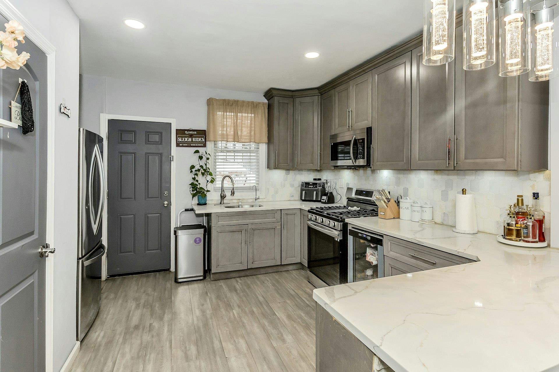 111-32 147th Street Queens, NY 11435 - Photo 5 of 24 Kitchen with a sink, light stone counters, stainless steel appliances, light wood-style floors, and decorative backsplash