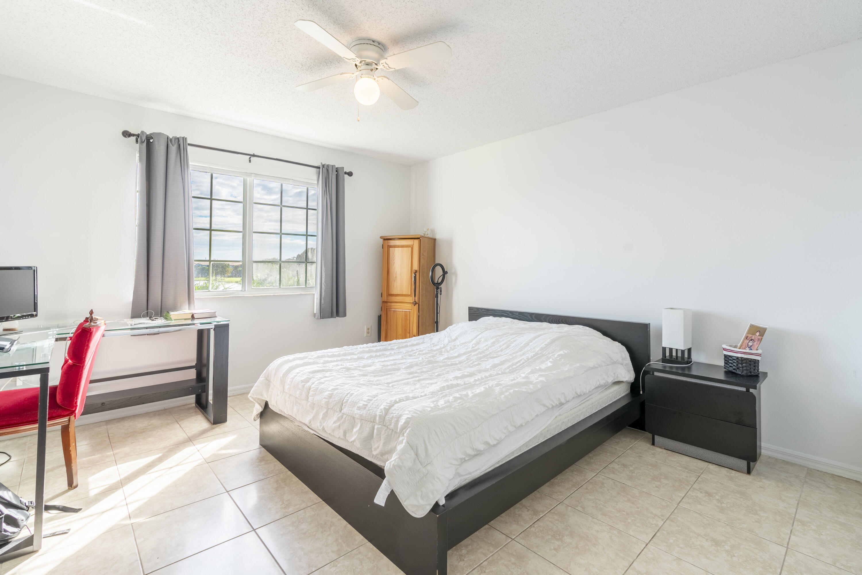 5031 Wiles Road, Unit 304 Coconut Creek, FL 33073 - Photo 43 of 55 a bedroom with a bed table chair and a window