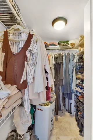 a view of walk in closet with clothes and shoes