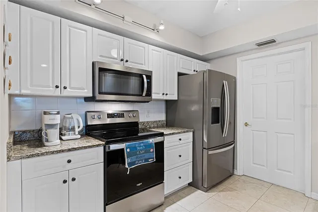 a kitchen with granite countertop a refrigerator stove and microwave