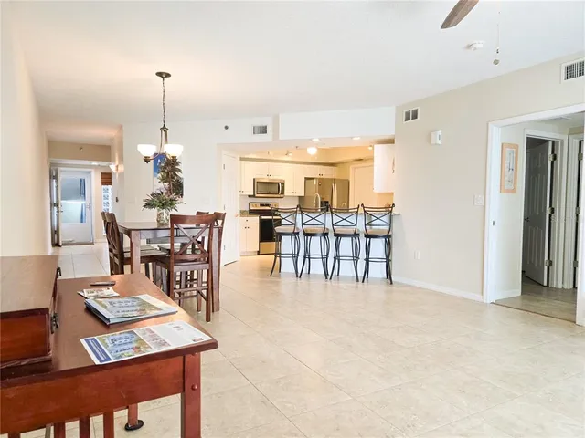 a view of a dining room and livingroom with furniture wooden floor a rug a painting and a chandelier