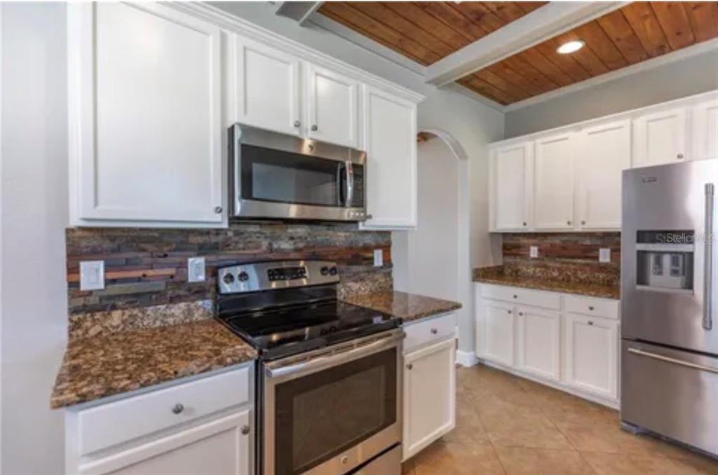 6914 Quiet Creek Drive Bradenton, FL 34212 - Photo 7 of 31 a kitchen with stainless steel appliances granite countertop a stove microwave and sink