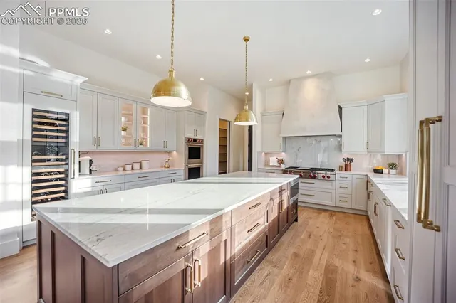 a large kitchen with kitchen island a stove a sink a center island a refrigerator and a wooden floor