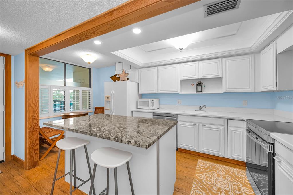 9495 Blind Pass Road, Unit 205 St. Pete Beach, FL 33706 - Photo 17 of 71 a kitchen with stainless steel appliances granite countertop a sink and cabinets
