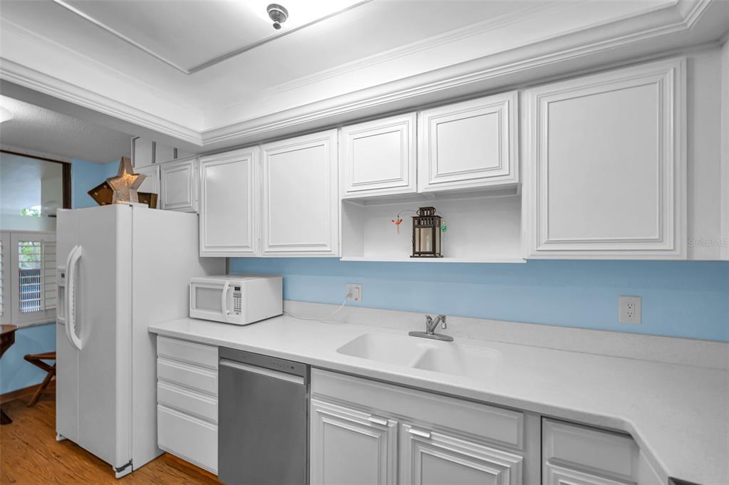9495 Blind Pass Road, Unit 205 St. Pete Beach, FL 33706 - Photo 18 of 71 a kitchen with stainless steel appliances white cabinets and a refrigerator