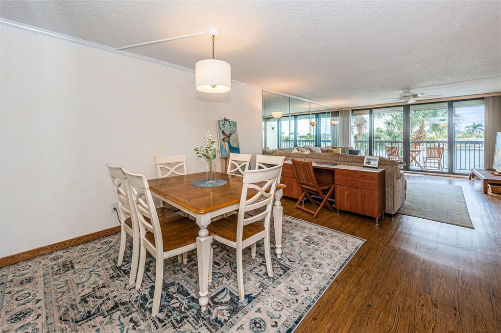 9495 Blind Pass Road, Unit 205 St. Pete Beach, FL 33706 - Photo 25 of 71 a view of a dining room with furniture window and wooden floor