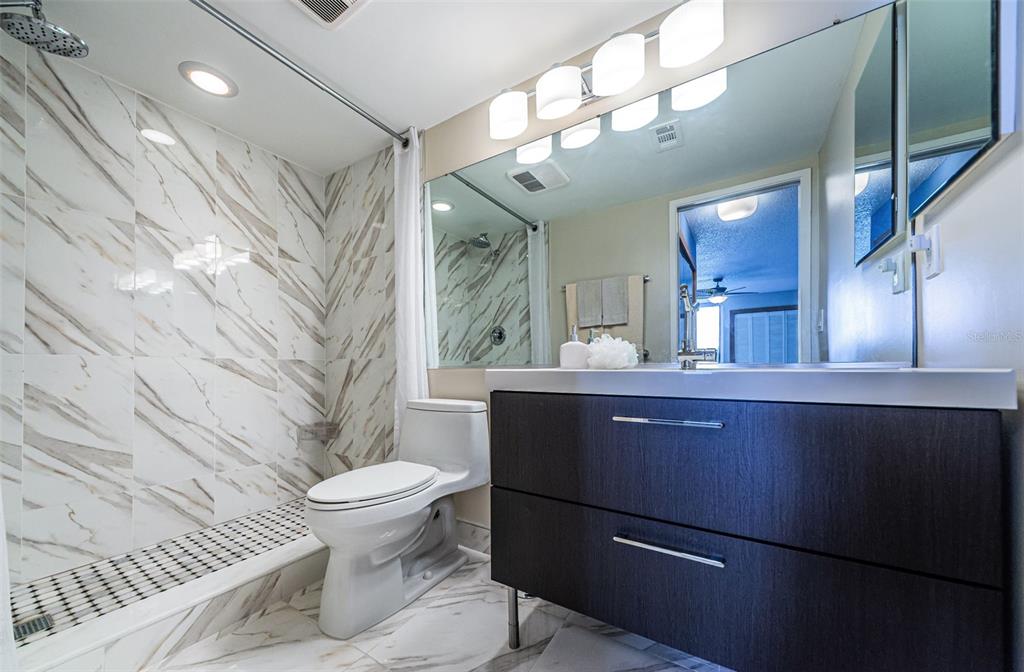 9495 Blind Pass Road, Unit 205 St. Pete Beach, FL 33706 - Photo 39 of 71 a bathroom with a toilet a sink and mirror