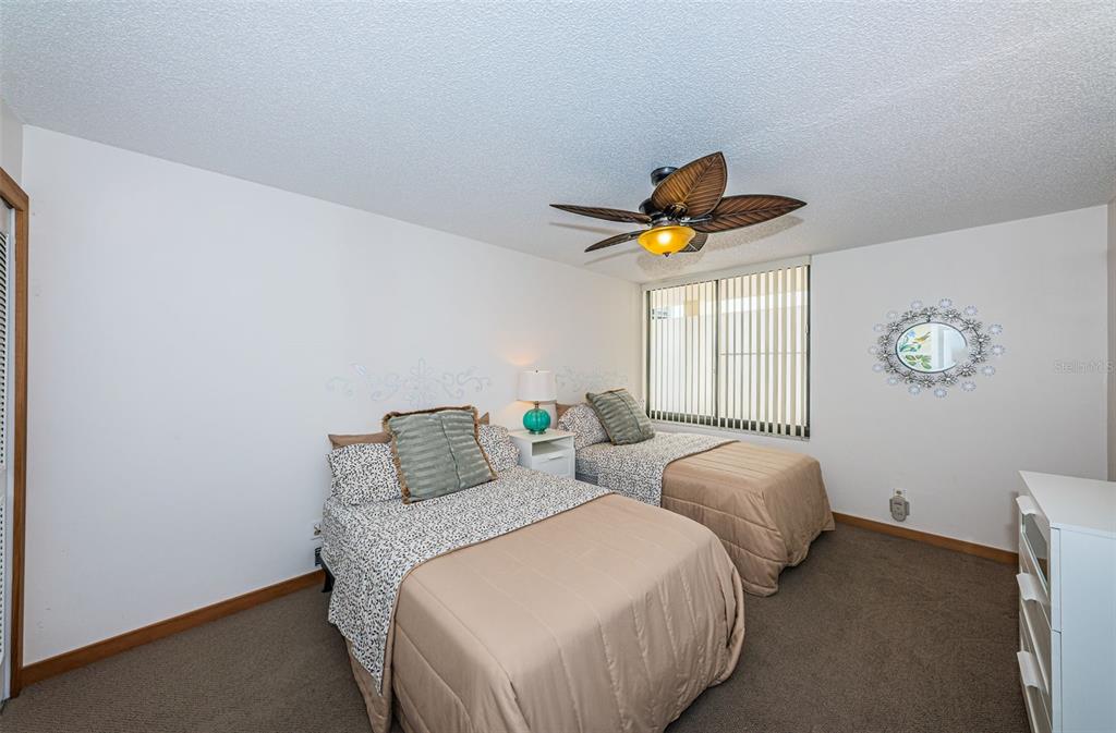 9495 Blind Pass Road, Unit 205 St. Pete Beach, FL 33706 - Photo 43 of 71 a bedroom with two beds and a chandelier