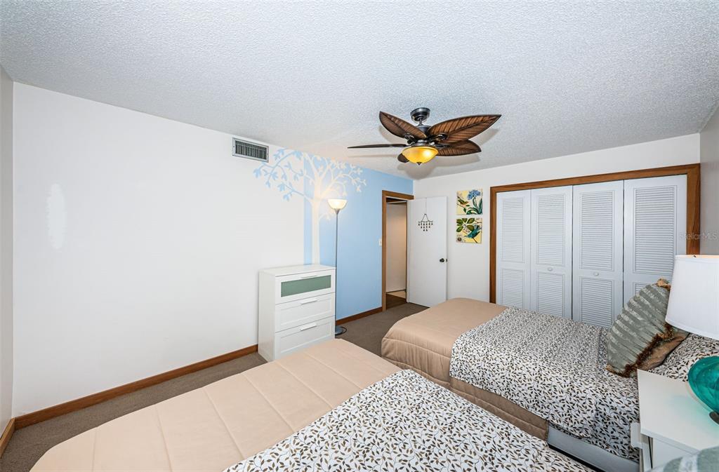 9495 Blind Pass Road, Unit 205 St. Pete Beach, FL 33706 - Photo 44 of 71 a bedroom with a bed and a ceiling fan