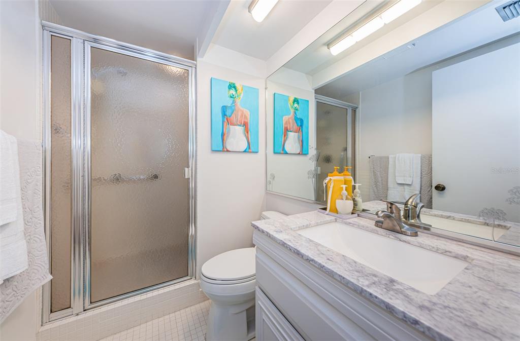 9495 Blind Pass Road, Unit 205 St. Pete Beach, FL 33706 - Photo 45 of 71 a bathroom with a granite countertop sink toilet and shower
