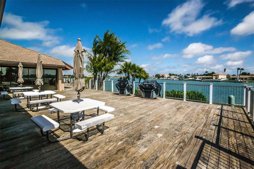 9495 Blind Pass Road, Unit 205 St. Pete Beach, FL 33706 - Photo 55 of 71 a view of a patio with a dining table and chairs with wooden floor and fence
