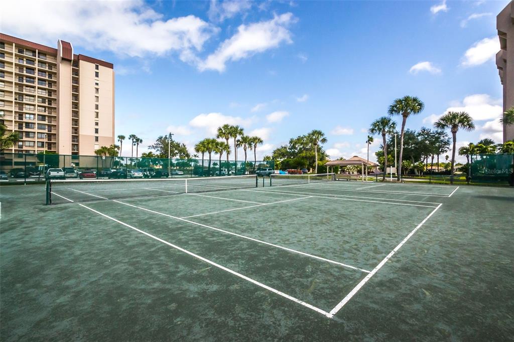9495 Blind Pass Road, Unit 205 St. Pete Beach, FL 33706 - Photo 62 of 71 a view of a tennis ground with large trees