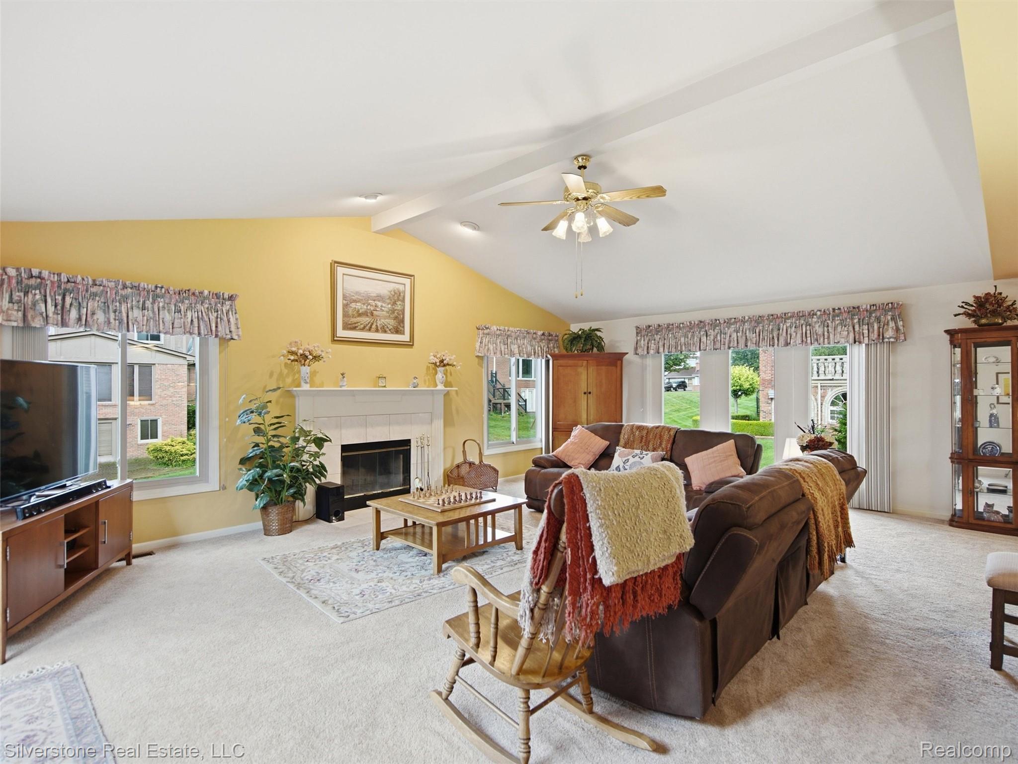 6577 Edith Court Troy, MI 48085 - Photo 12 of 61 Spacious living room featuring a vaulted ceiling with exposed beams, light-toned carpeting, and multiple windows providing natural light