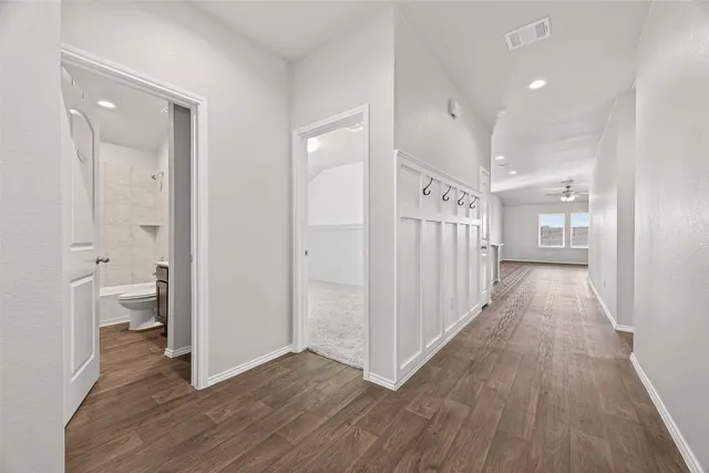 a view of a hallway with wooden floor and a bathroom