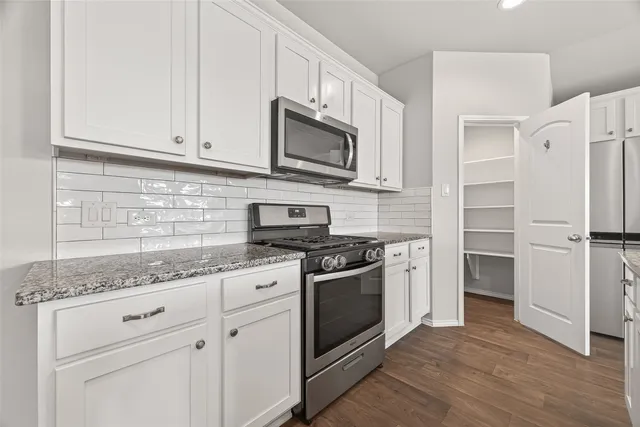 a kitchen with stainless steel appliances granite countertop a stove a microwave and a white cabinets