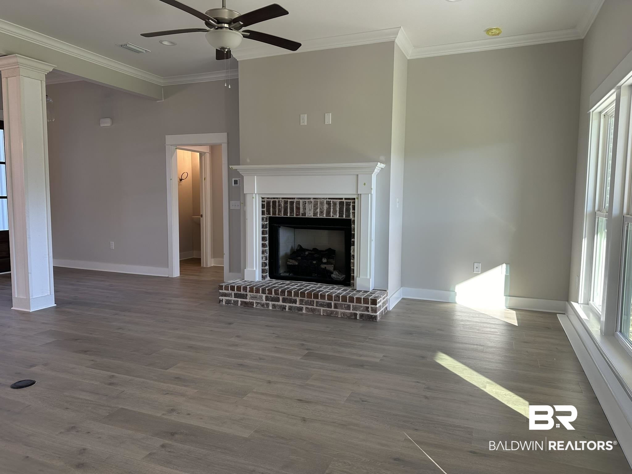 23582 Travis Stock Street, Unit 48 Foley, AL 36535 - Photo 14 of 51 Unfurnished living room featuring hardwood / wood-style floors, a brick fireplace, and crown molding