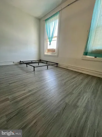 an empty room with wooden floor and window