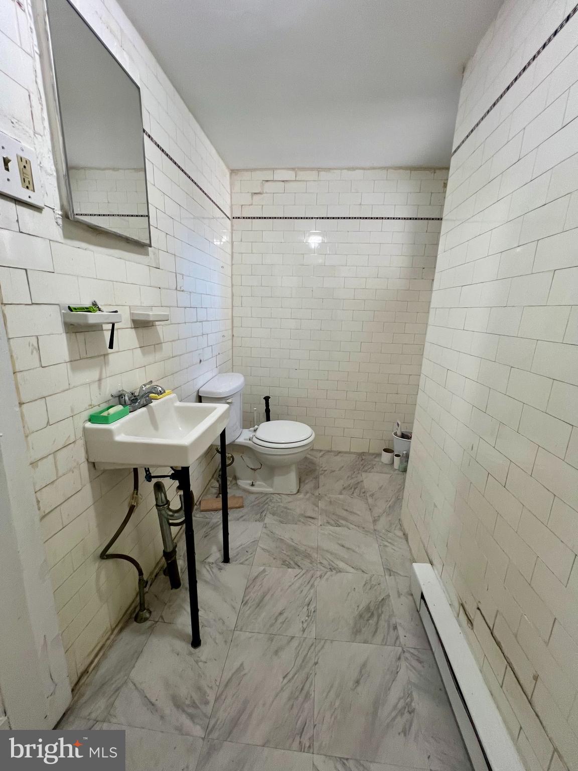 3140 North Broad Street, Unit 2F Philadelphia, PA 19132 - Photo 7 of 7 a bathroom with a sink a toilet and a mirror
