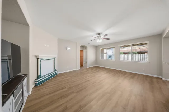 a view of an empty room with a window and wooden floor