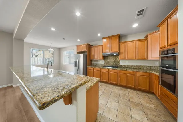 a large kitchen with stainless steel appliances granite countertop a large counter top and a refrigerator
