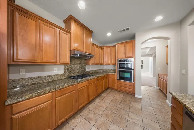 a large kitchen with stainless steel appliances granite countertop a refrigerator and a stove top oven