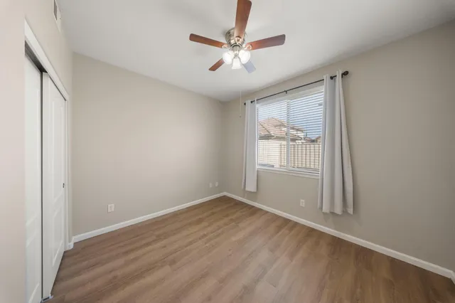 an empty room with wooden floor and ceiling fan