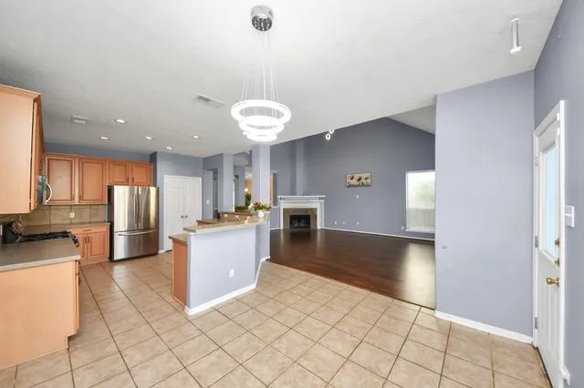 a kitchen with stainless steel appliances kitchen island granite countertop a refrigerator a stove and white cabinets with wooden floor