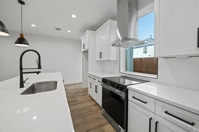 a view of a kitchen with kitchen island a sink wooden floor and a refrigerator