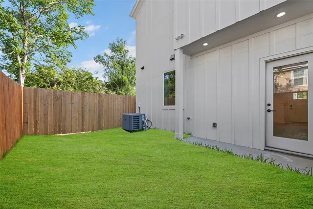 a view of an empty room and kitchen view with wooden floor