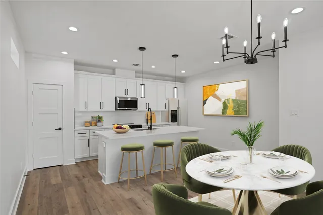 a kitchen with stainless steel appliances a table and chairs in it