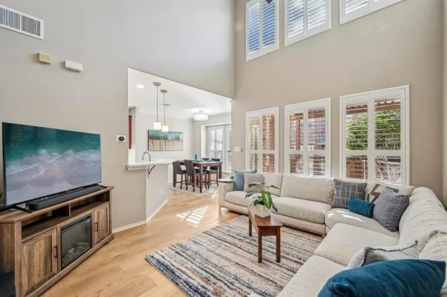 a living room with stainless steel appliances kitchen island granite countertop a stove a sink and a wooden floors