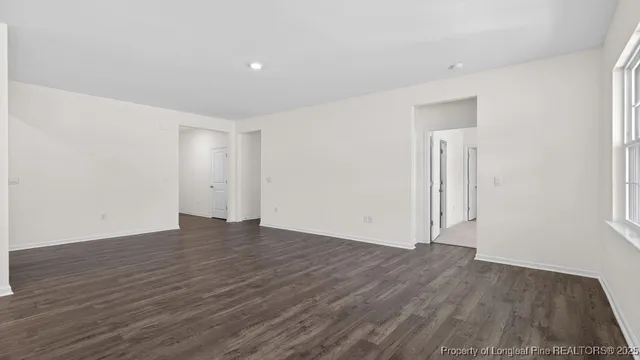 a view of an empty room with wooden floor and closet