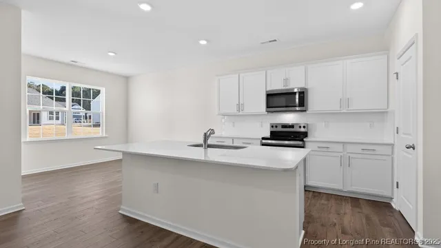 a kitchen with granite countertop white cabinets and black stainless steel appliances